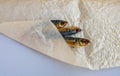 A smoked horse mackerel close-up lies wrapped on a crumpled paper background Royalty Free Stock Photo