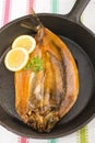 Smoked kipper with lemon and parsley in a pan Royalty Free Stock Photo