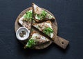 Smoked mackerel and cream cheese bruschetta on wooden chopping board on dark background, top view. Delicious appetizers Royalty Free Stock Photo