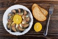 Smoked mackerel, lemon in plate, bread, fork on wooden table. Top view Royalty Free Stock Photo