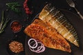 Smoked marinated mackerel fillets or fillet herring fish with spices, greens and slice of bread on plate over dark stone Royalty Free Stock Photo