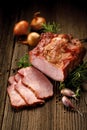 Smoked meats, sliced smoked pork loin on a wooden table with addition of fresh herbs and aromatic spices.