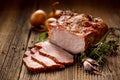 Smoked meats, sliced smoked pork loin on a wooden table with addition of fresh herbs and aromatic spices.
