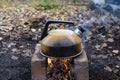 Smoked metal kettle boils on fire on bricks outdoors Royalty Free Stock Photo