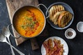 Smoked paprika lentil soup with grilled cheese sandwiches and crispy bacon on a dark background, top view. Delicious comfort food