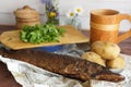 Smoked pike fish lies on the newspaper on the table