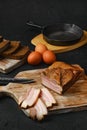 Smoked bacon with brown bread and eggs on wooden cutting board Royalty Free Stock Photo