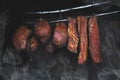 Smoked pork meat in smoker on dark background.