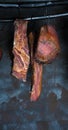 Smoked pork meat in smoker on dark background.