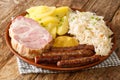 Smoked pork neck and sausages with cabbage Sauerkraut boiled potatoes and mustard closeup in the plate. Horizontal
