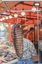 Smoked pork ribs are hang on hook at the meat market, butcher on the background, close up and vertical image