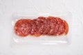 Smoked salami sausages slices in vacuum pack, on white stone table background, top view flat lay, with copy space for text Royalty Free Stock Photo