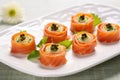 smoked salmon rosettes served with caper berries on a white plate