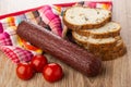 Smoked sausage on napkin, tomato cherry, pieces of bread on table