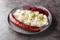 Smoked sausage with potatoes in cream sauce with dill and boiled beets close-up on a plate. Horizontal Royalty Free Stock Photo