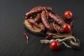 Smoked sausage with rosemary, pepper, tomatoes and garlic on a black background. Royalty Free Stock Photo