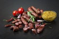 Smoked sausage with rosemary, pepper, tomatoes and garlic on a black background. Royalty Free Stock Photo