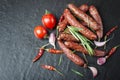 Smoked sausage with rosemary, pepper, tomatoes and garlic on a black background. Royalty Free Stock Photo