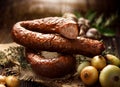 Smoked sausage on a wooden rustic table with addition of fresh aromatic herbs and spices