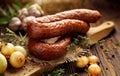 Smoked sausage on a wooden rustic table with addition of fresh aromatic herbs and spices