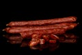 Smoked spicy sausage isolated on black glass