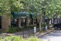 The Smokers Den, retails shops and restaurants along a sidewalk with lush green trees and plants in Athens Georgia USA