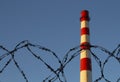 Smokestack against a clear blue sky and a metal barbed wire in front. copyspace for text Royalty Free Stock Photo