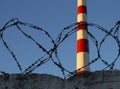 Smokestack against a clear blue sky and a metal barbed wire in front. copyspace for text Royalty Free Stock Photo