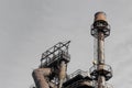 Smokestack with ladders and catwalks against a grey sky, steel mill