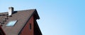 Smokestack, tile roof, roof window and wooden facade of a country cottage against the sky Royalty Free Stock Photo