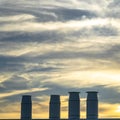 Smokestacks against dramatic cloudy sky at sunset