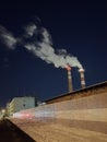 Chimneys that emit smoke into the night sky and a long fence. Release of smoke into the environment. Royalty Free Stock Photo