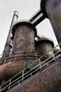 Smokestacks, tubes, and pipes with heavy rust patina, catwalks