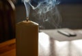 Smoking candle on wooden table after blowing off the flame Royalty Free Stock Photo