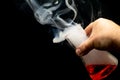 smoking chemicals, a glass flask with a chemical liquid held in the hand on a black background