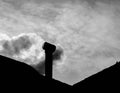 A smoking chimney on the roof of a house.