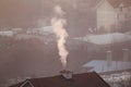 Smoking chimneys at roofs of houses emits smoke, smog at sunrise, pollutants enter atmosphere. Environmental disaster.