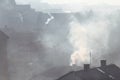 Smoking chimneys at roofs of houses emits smoke, smog at sunrise, pollutants enter atmosphere. Environmental disaster. Royalty Free Stock Photo