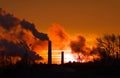 Smoking factory chimneys in morning back lit by rising sun Royalty Free Stock Photo