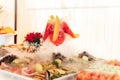 Smoking glass at fruit and vegetable buffet table. Closeup of glass of red beverage with white dense fog. Chemical