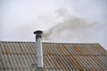 The smoking iron chimney of an old house in the evening Royalty Free Stock Photo