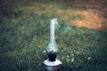 A smoking old kerosene lamp on a green grass. Royalty Free Stock Photo