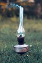 A smoking old kerosene lamp on a green grass. Royalty Free Stock Photo