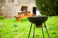 A smoking round grill on a background of green grass. Preparing for a picnic