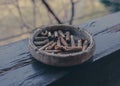 A clay ashtray with butts on a wooden terrace beam Royalty Free Stock Photo