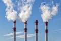 Smoking tall pipes of a thermal power plant against a blue sky Royalty Free Stock Photo