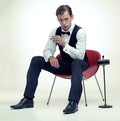 Smoking, tuxedo and portrait of man in studio with red chair and cigarette for elegant and fancy outfit. Serious Royalty Free Stock Photo