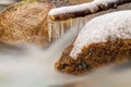 Smoky cold water of mountain stream in winter time. Long crystal icicles are hanging above milky water level. Royalty Free Stock Photo