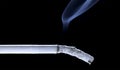 Smoldering cigarette on a black background Royalty Free Stock Photo
