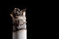 Smoldering cigarette with smoke close-up macro on a black background Royalty Free Stock Photo